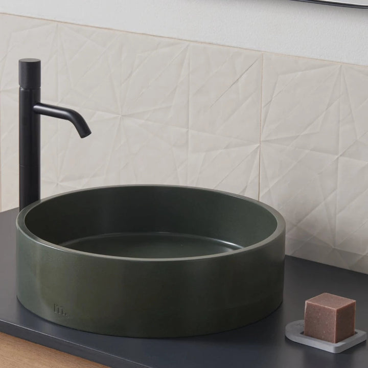 A mudd. concrete Odet Basin LG bathroom sink with a black faucet and soap dispenser.
