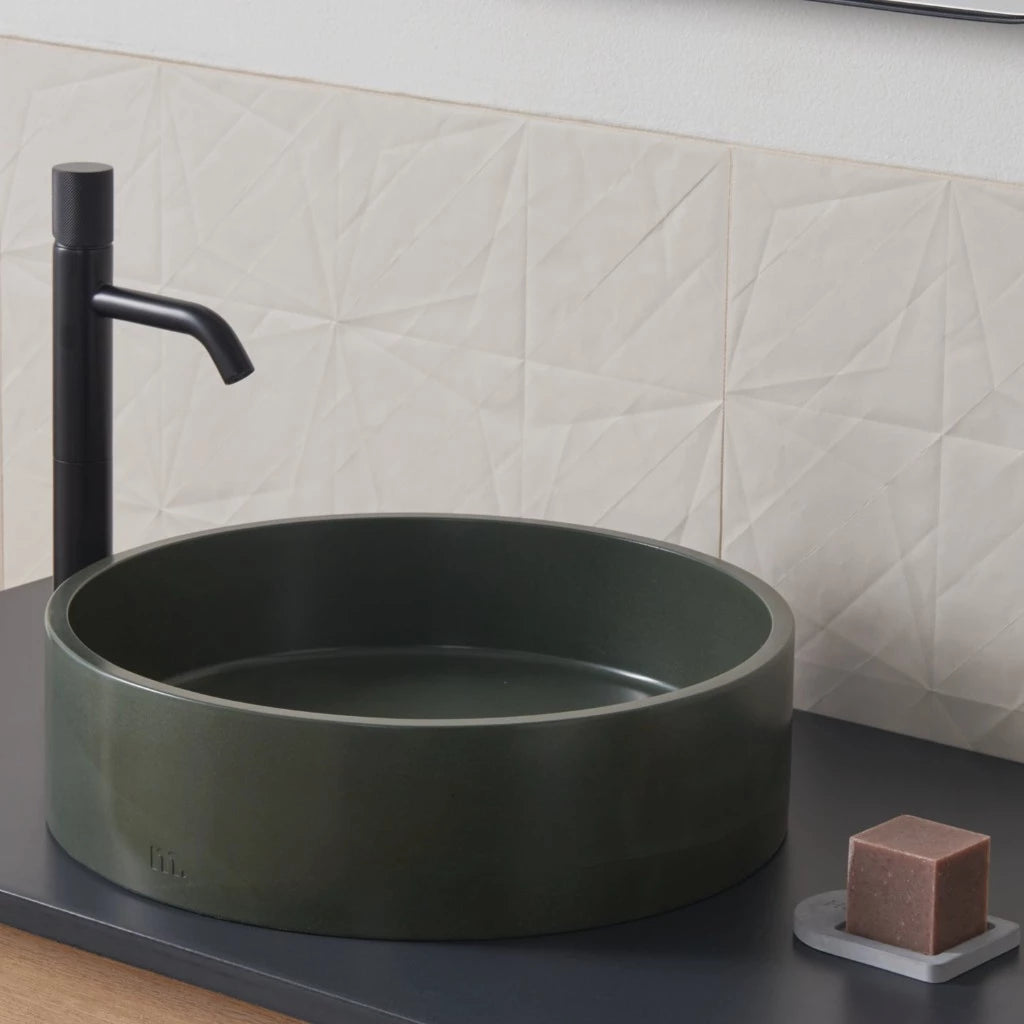 A mudd. concrete Odet Basin LG bathroom sink with a black faucet and soap dispenser.