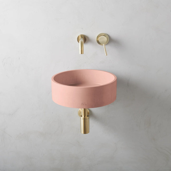 a mudd. concrete Odet Basin SM Affix with a gold faucet next to it.