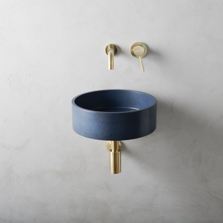 A mudd. concrete Odet Basin SM Affix with a gold faucet next to it.