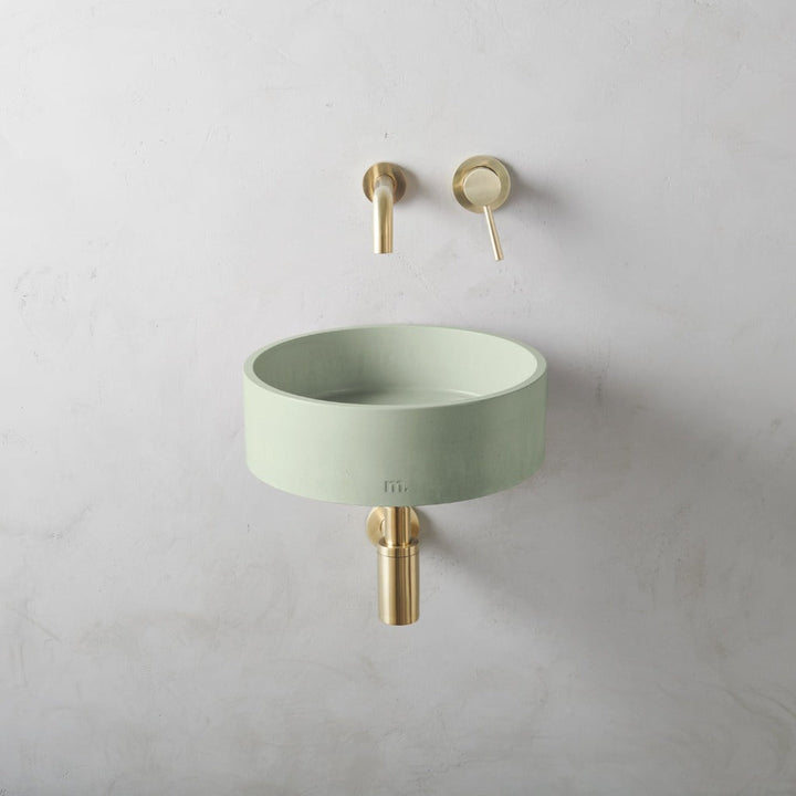 A Mudd. Concrete Odet Basin SM Affix with a gold faucet next to it.