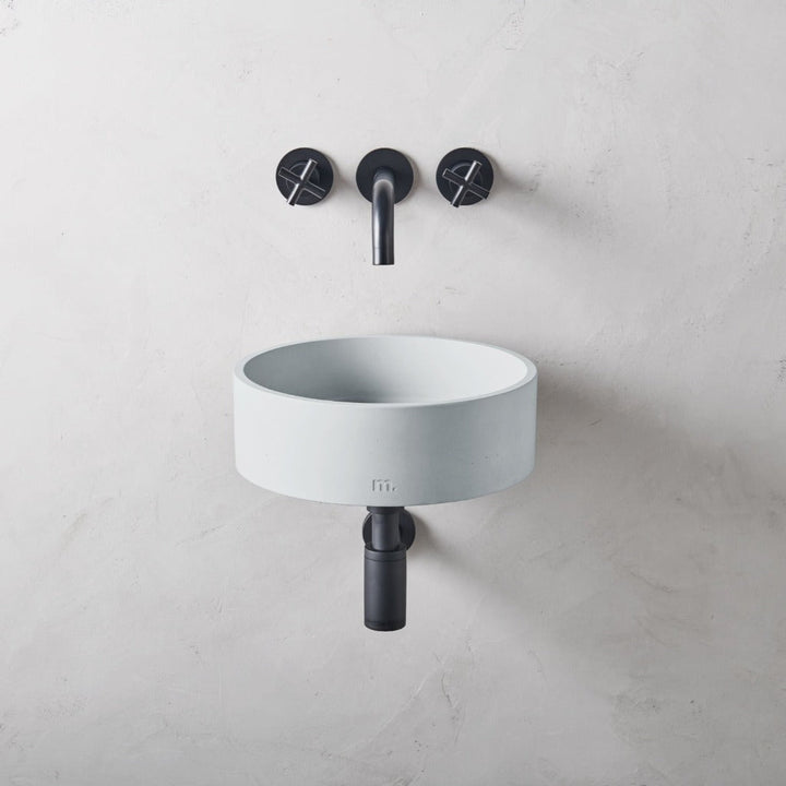 An Odet Basin SM Affix sink sitting next to a black mudd. concrete faucet.