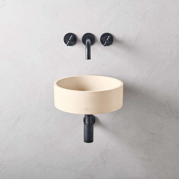 A mudd. concrete Odet Basin SM Affix with two black faucets on the wall.