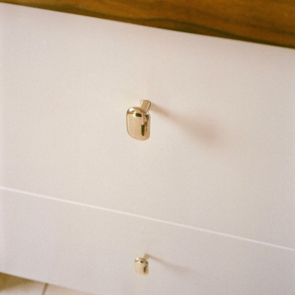 Brass Maha Alavi Oval knobs on white drawers.