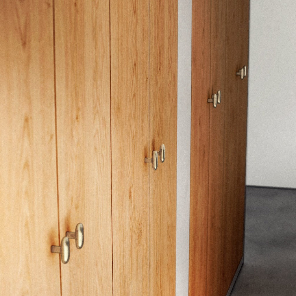 Brass Maha Alavi Oval knobs on a wood cabinet.