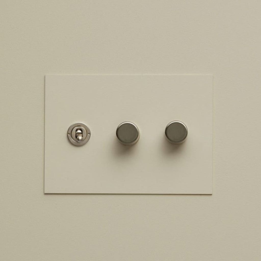 Cream Forbes & Lomax painted switch plate with a toggle and two dimmers.