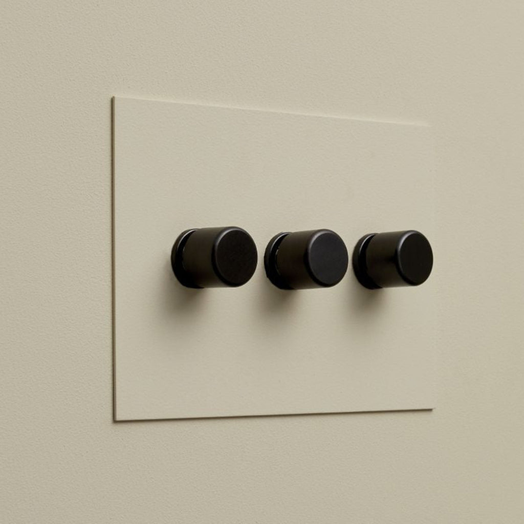 Cream Forbes & Lomax painted switch plate with three black dimmers.