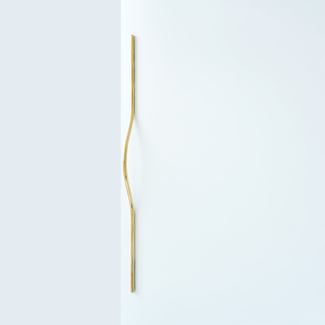 Elegant long brass line handle on a white door.