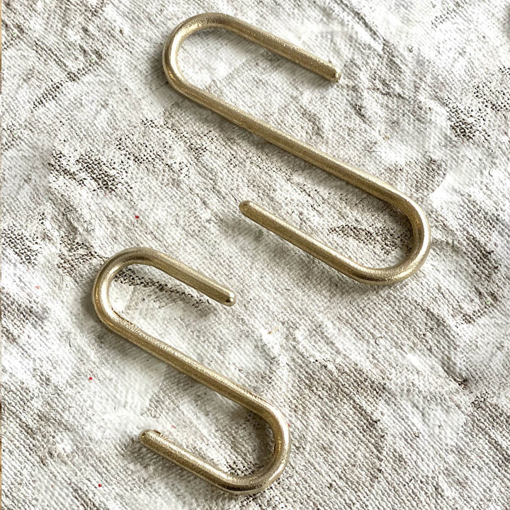 A pair of Shayne Fox Pyra S hooks sitting on top of a white cloth.
