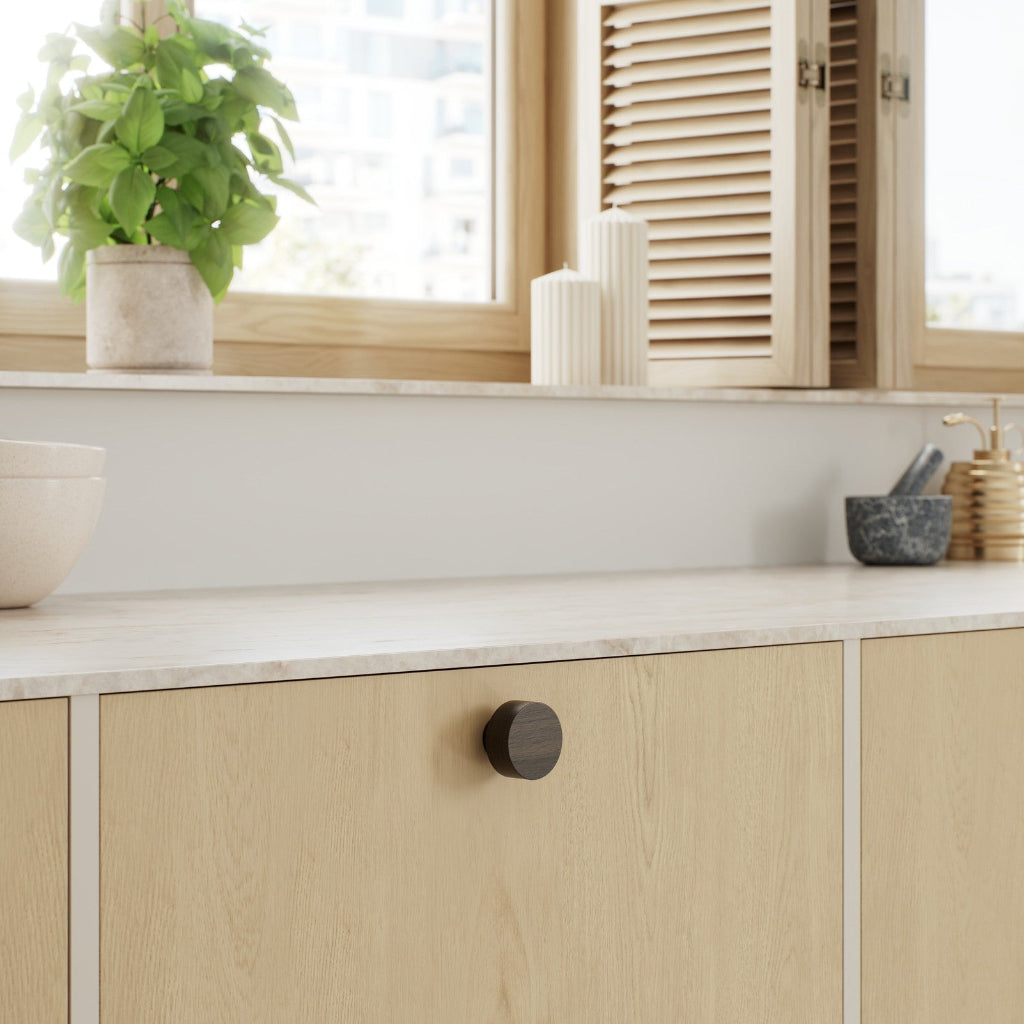 Dark brown oak Furnipart Row cabinet knob on a light oak cabinet door.