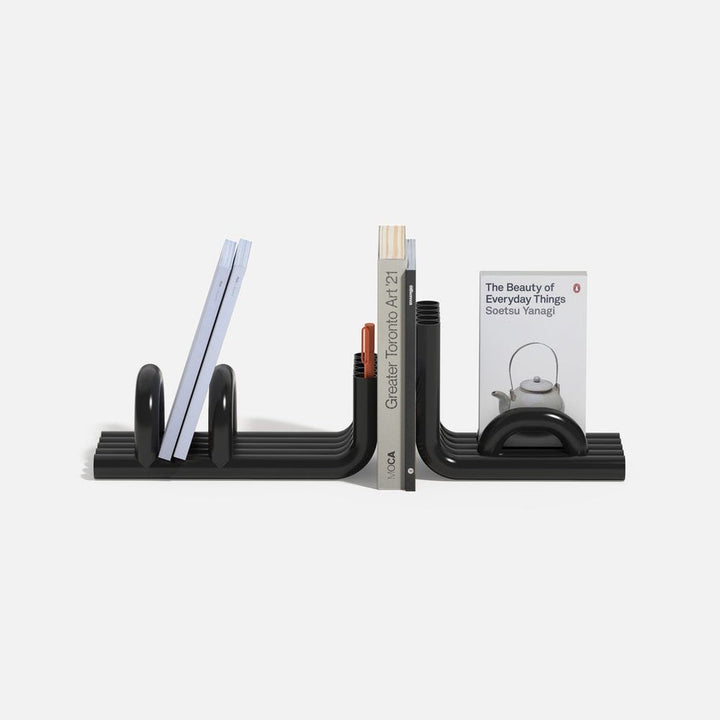 Black TUBE Bookends photographed on a white background with a collection of books in between on a white background