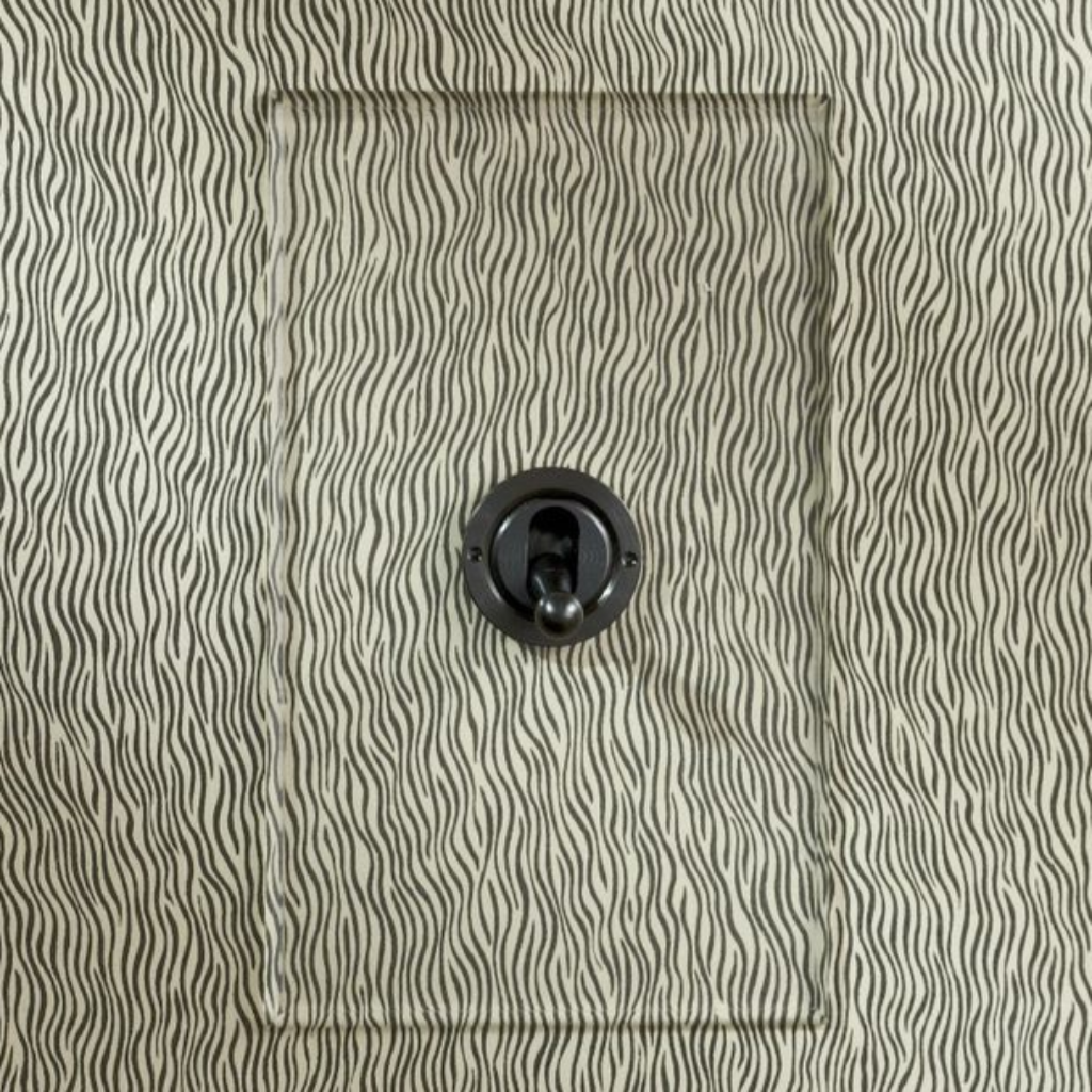 Forbes & Lomax invisible plate toggle switch on a papered wall.