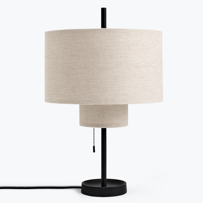 A round, tiered table lamp with a thin, black base