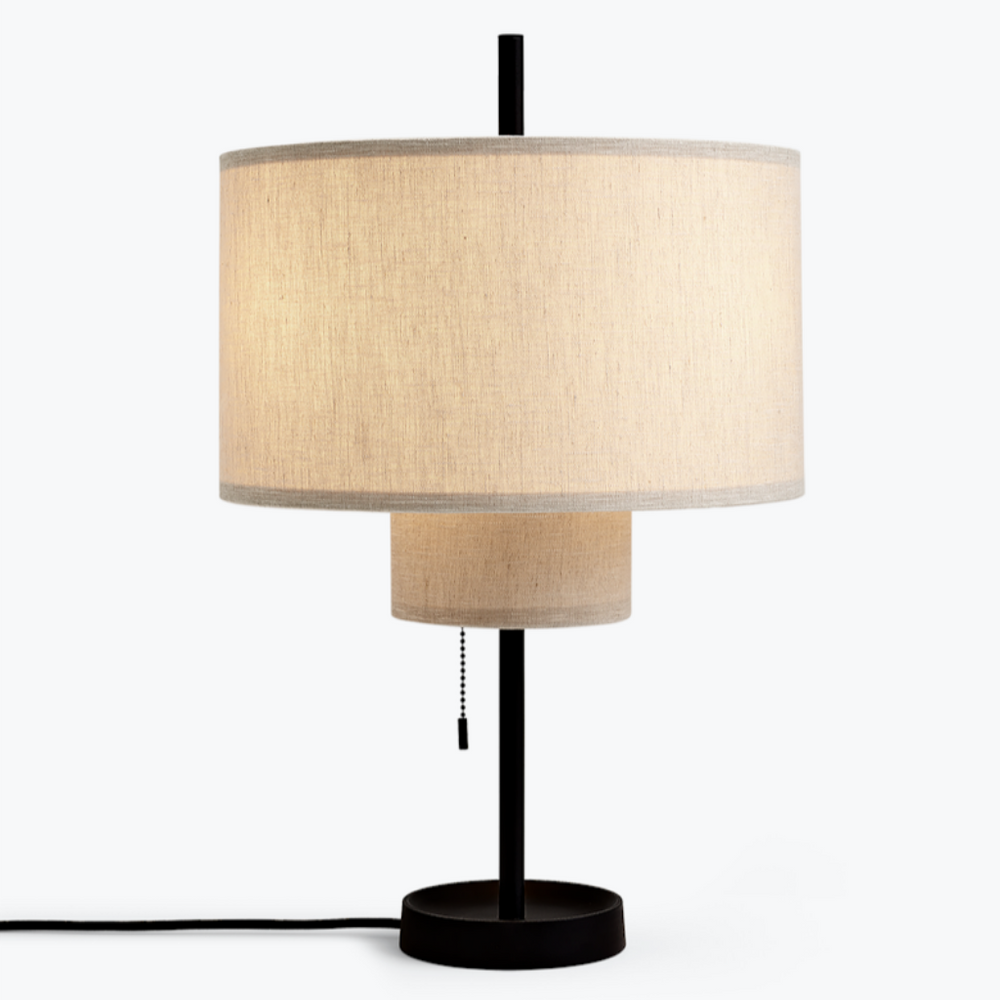 A round, tiered table lamp with a thin, black base