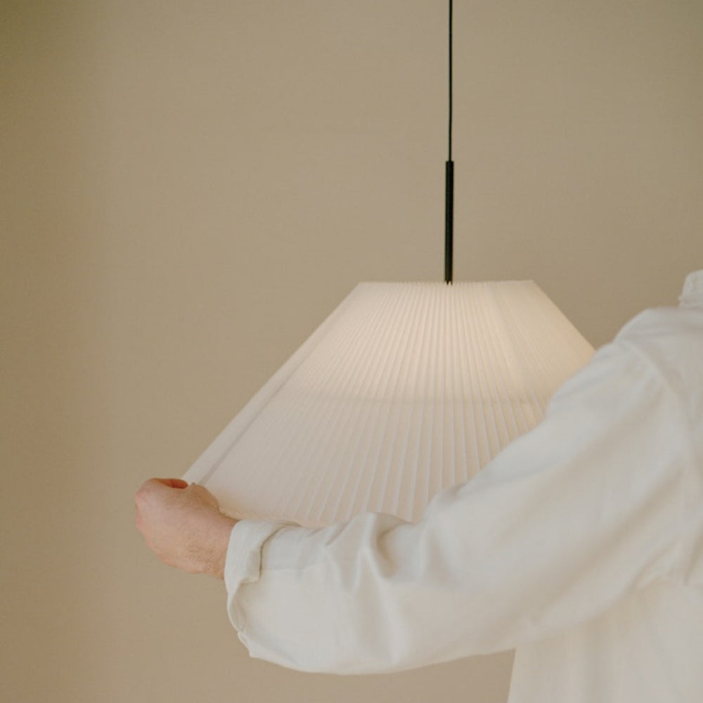 Small pendant lamp hung from ceiling with person adjusting
