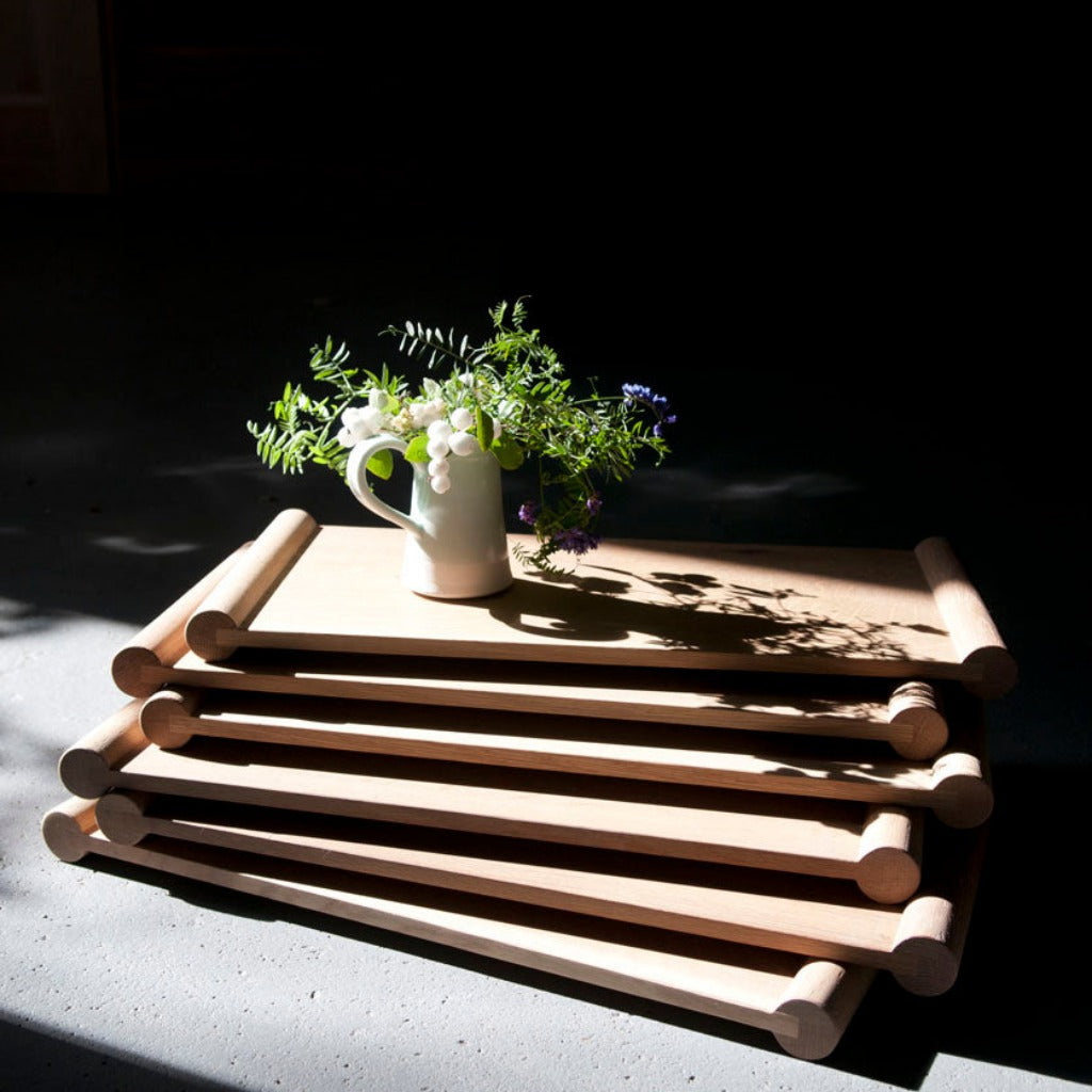 Rectangular wooden trays stacked with a vase of flowers on top