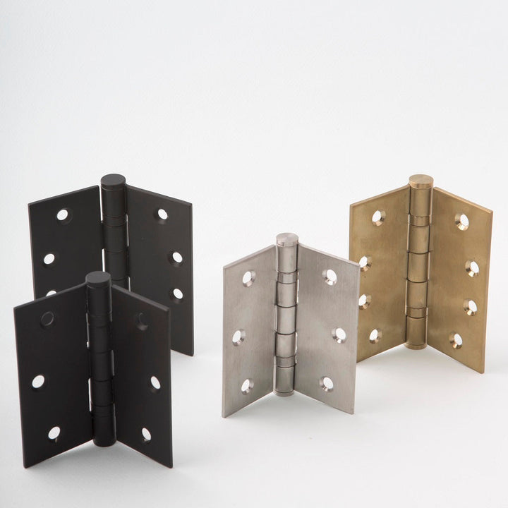 Group of 4 door hinges together in brass, steel, and black finishes. In different positions.