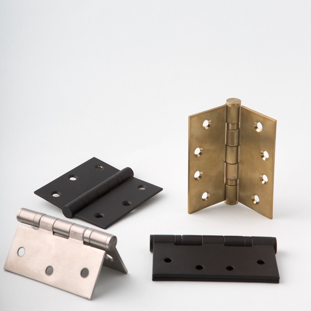 Group of 4 door hinges together in brass, steel, and black finishes. In different positions.