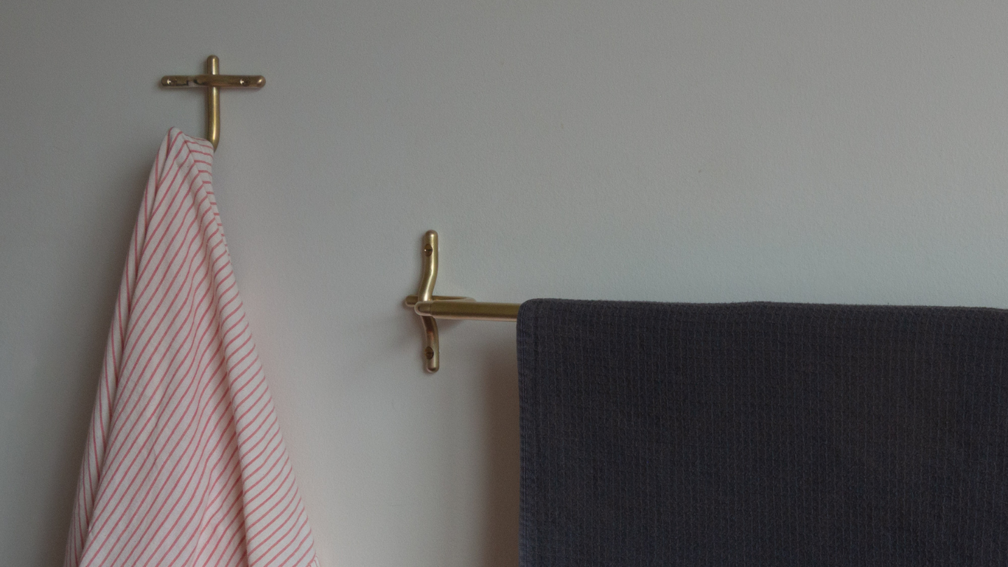 Handmade brass towel bar and hook with towels on them. 