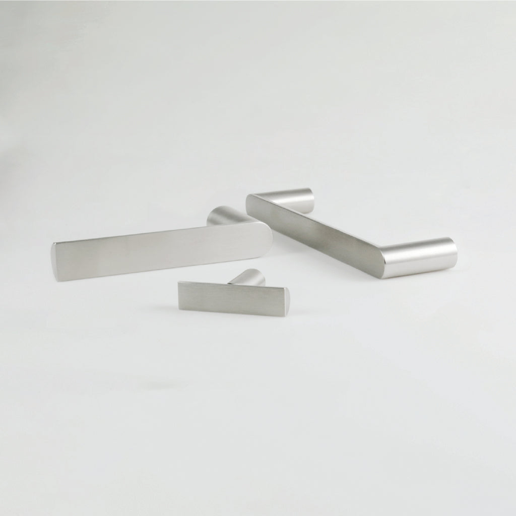 A couple of Formani ARC Cabinet Handles sitting on top of a white table.