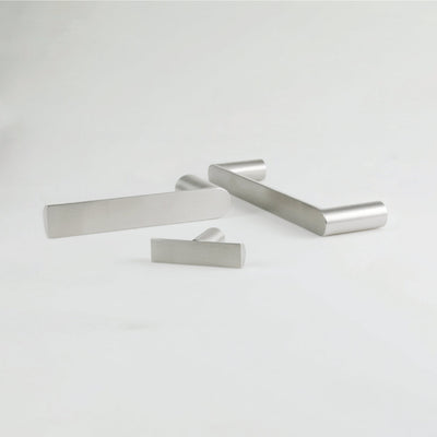 A couple of Formani ARC Lever Handles sitting on top of a white table.