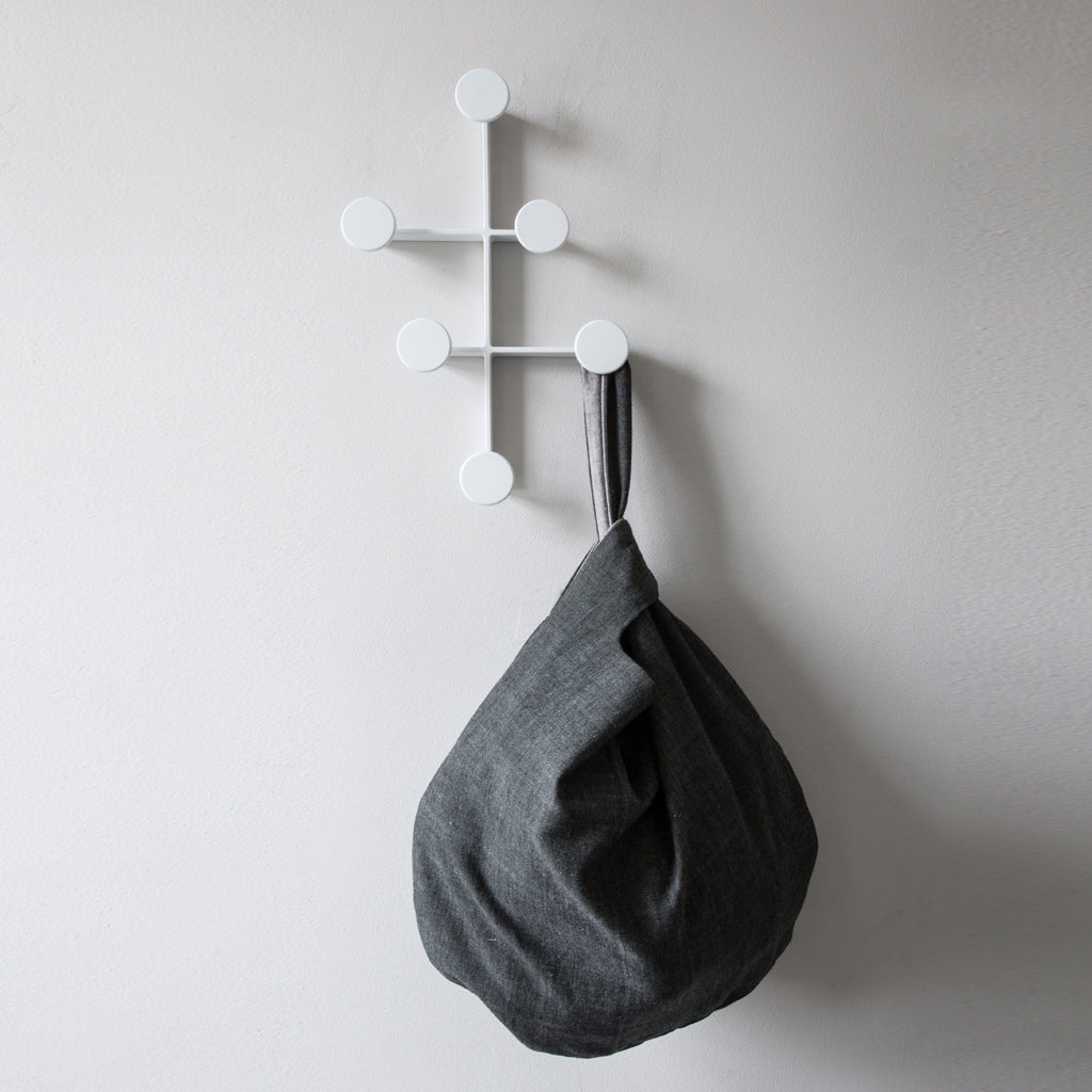 Modern and minimal white coat hanger with gray bag.