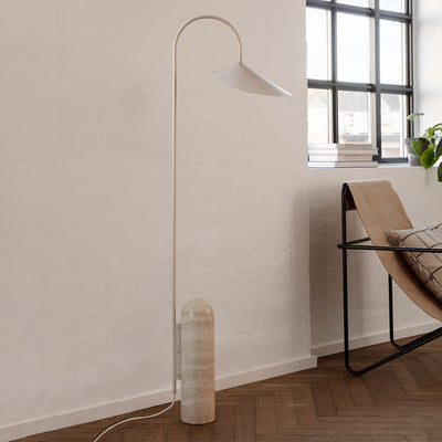 A Ferm Living Arum Floor Lamp next to a chair in a room.