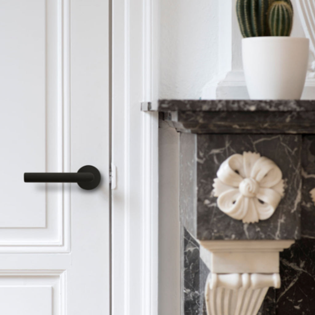 A white Formani door with a black BASICS LBIII-19 Door Lever handle on it.