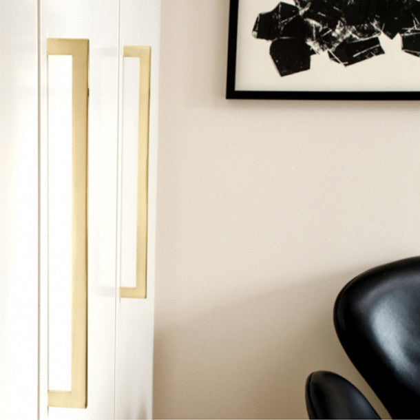 Long brass handles on modern wardrobe cabinet doors.