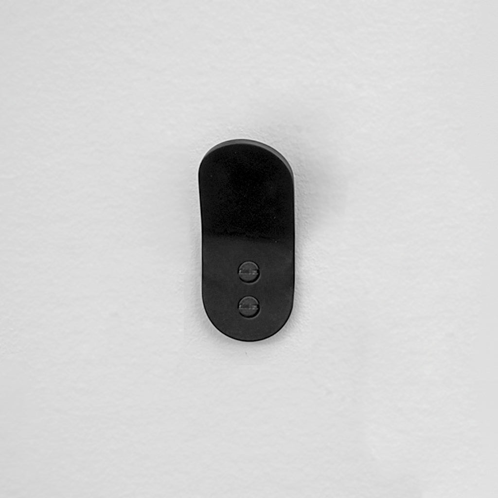 A close up of a BENDE Angle Hook button on a white wall by CSSN.