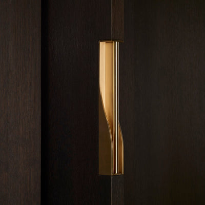 Elegant brass dressing handle on a dark wood door from an angle. Beautifully and functionally designed.