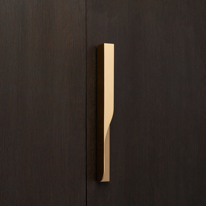 Elegant brass furniture pull handle on wood door from the front. Beautifully and functionally designed.