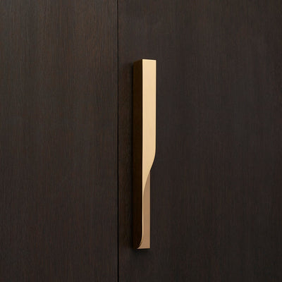 Elegant brass furniture pull handle on wood door from the front. Beautifully and functionally designed.