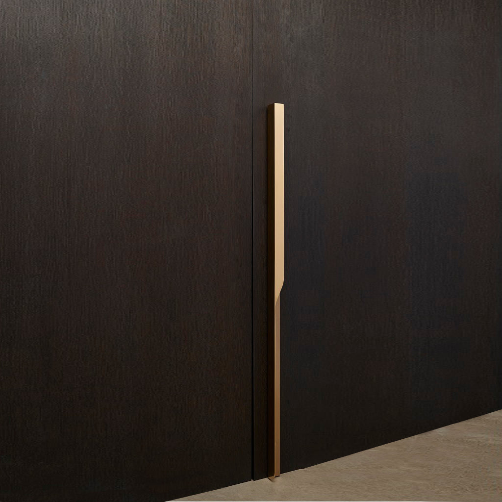 Elegant brass furniture pull handle on wood door at an angle. Beautifully and functionally designed.