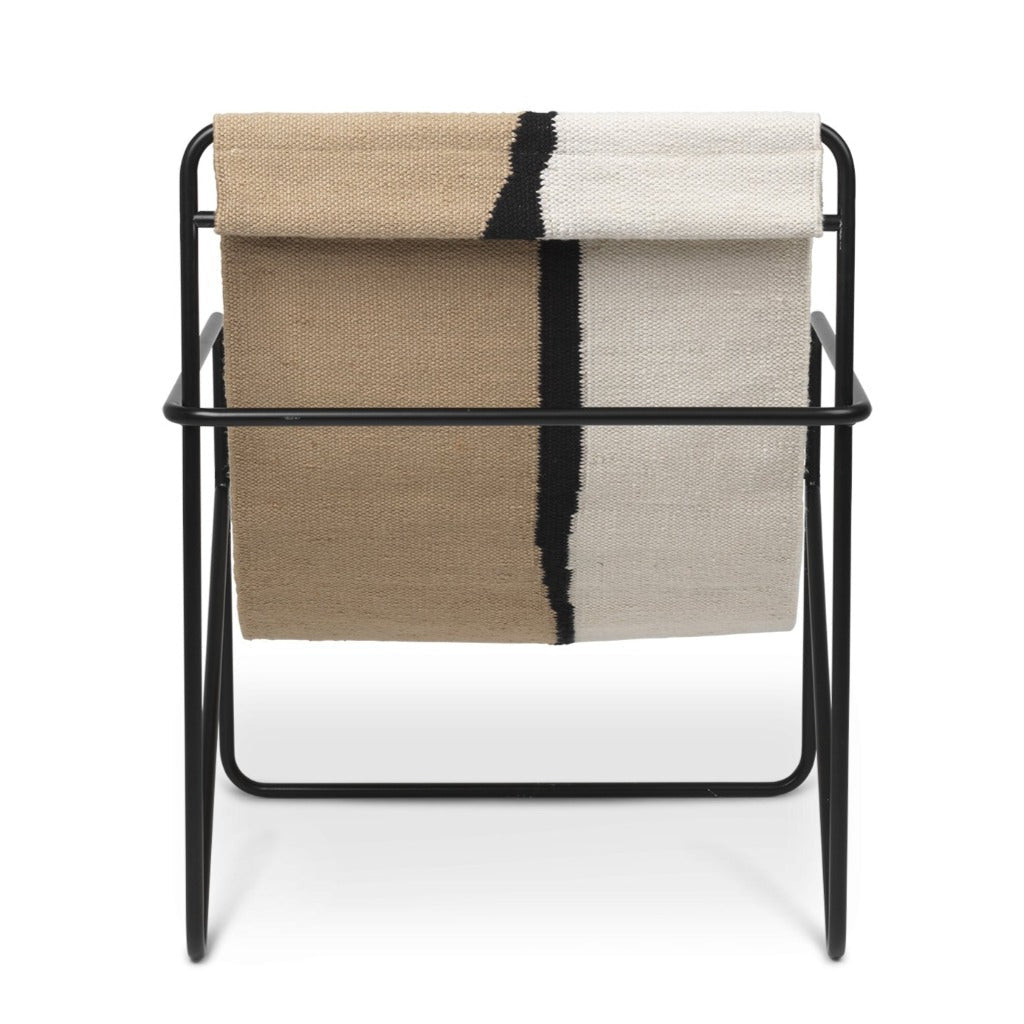 A Ferm Living Black Soil Desert Lounge Chair with a blanket on top of it.