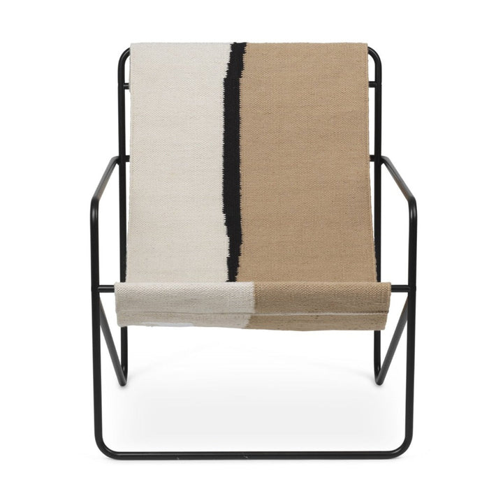 A Ferm Living Black Soil Desert Lounge Chair with a blanket on top of it.