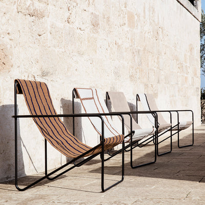 A row of Ferm Living Black Solid Desert Lounge Chairs sitting next to a wall.