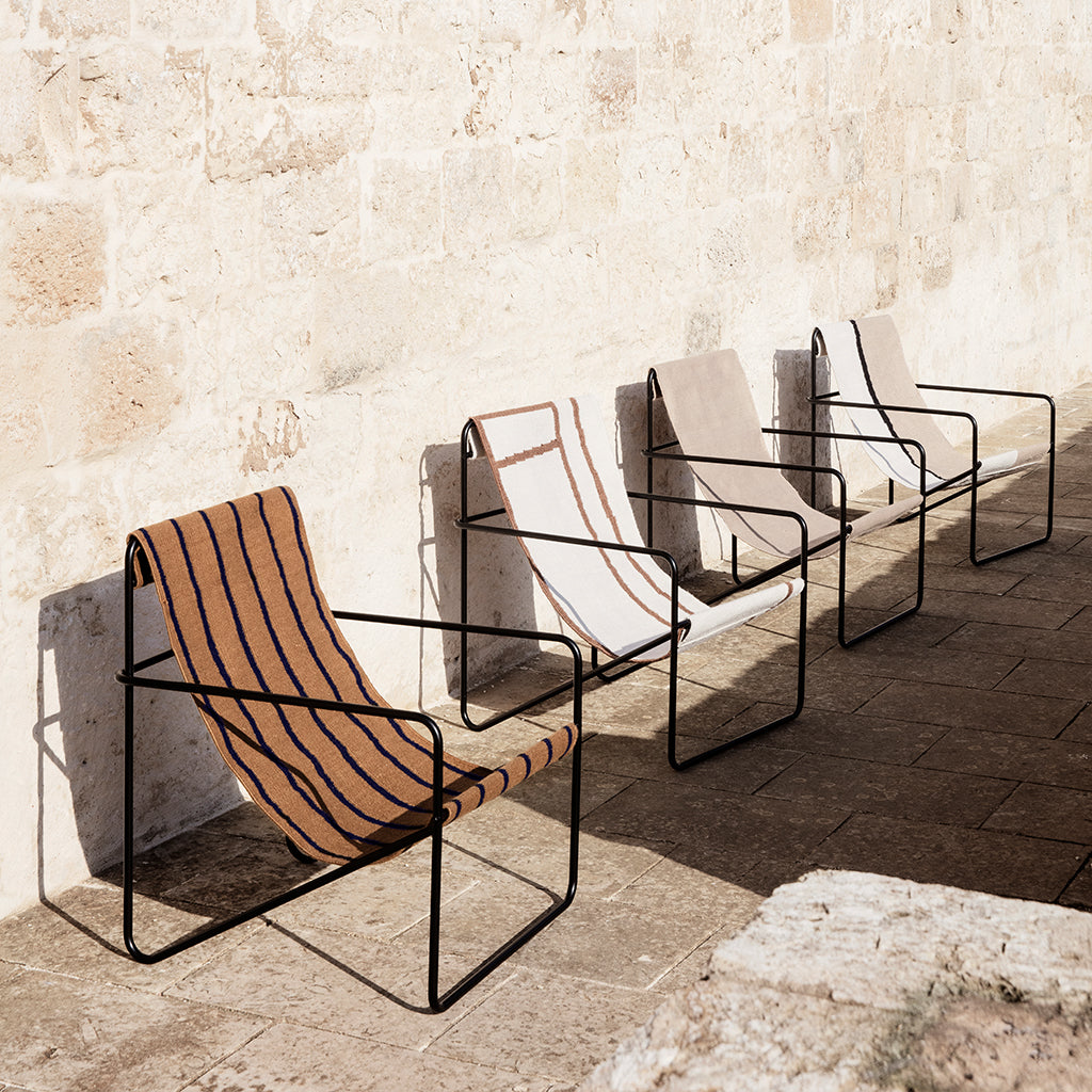 A row of Ferm Living Black Stripe Desert Lounge Chairs sitting next to a wall.