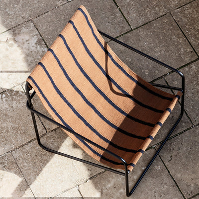 A Ferm Living Black Stripe Desert Lounge Chair that is sitting on the ground.