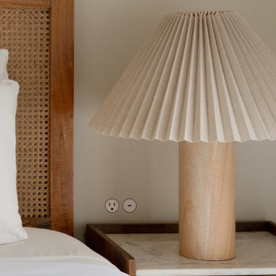 Bedroom with wooden headboard, white pillows, and a lamp on a nightstand.