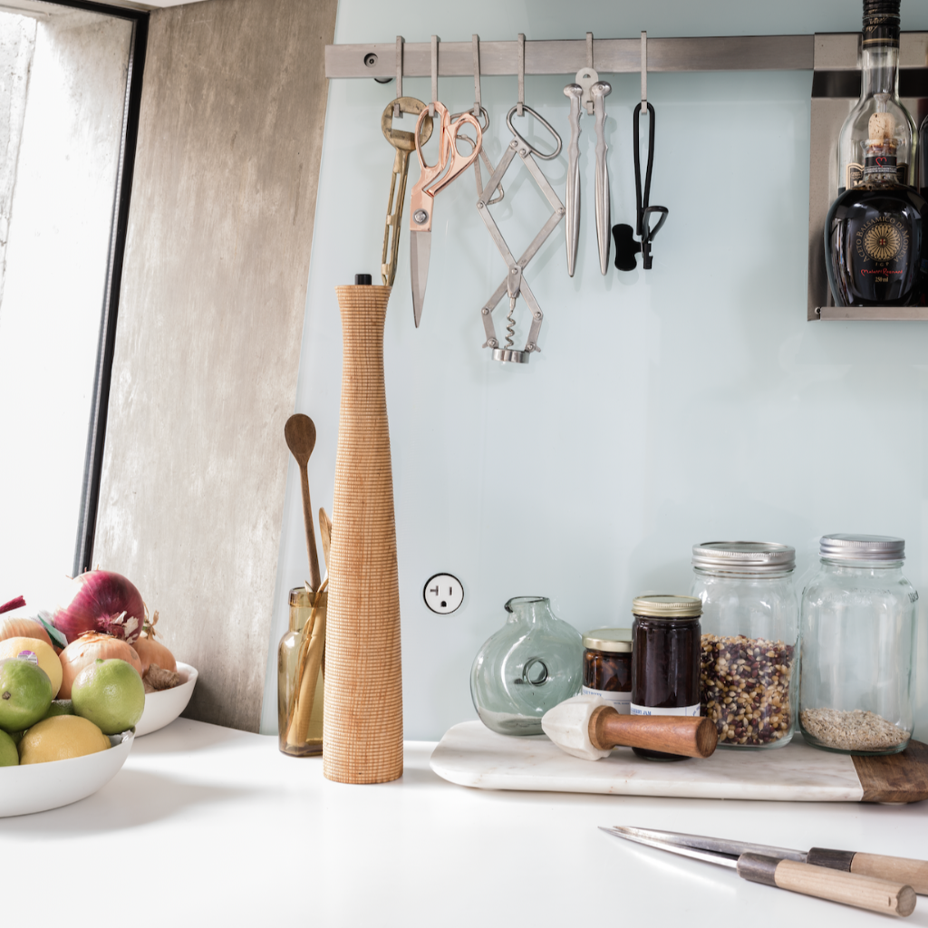 Modern kitchen counter with hanging rod of utensils and fruit and jars on a counter and a single Bocci22 flush outlet in the wall. 
