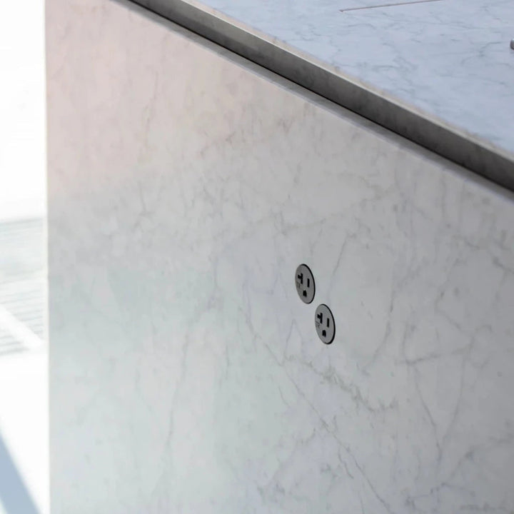 A close up of a Bocci 22: Alternate Material Mounting inset in a white marble kitchen island waterfall face. 