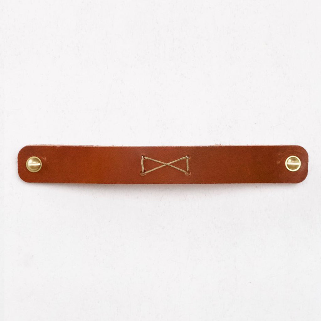 A Lostine Bow-Tie Leather Pull belt with a gold clasp.