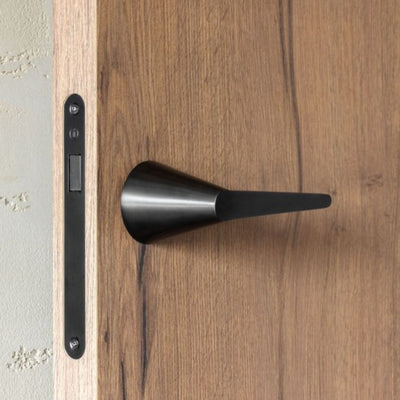 A close up of a Formani CONE Lever Handle 100-G on a wooden door.