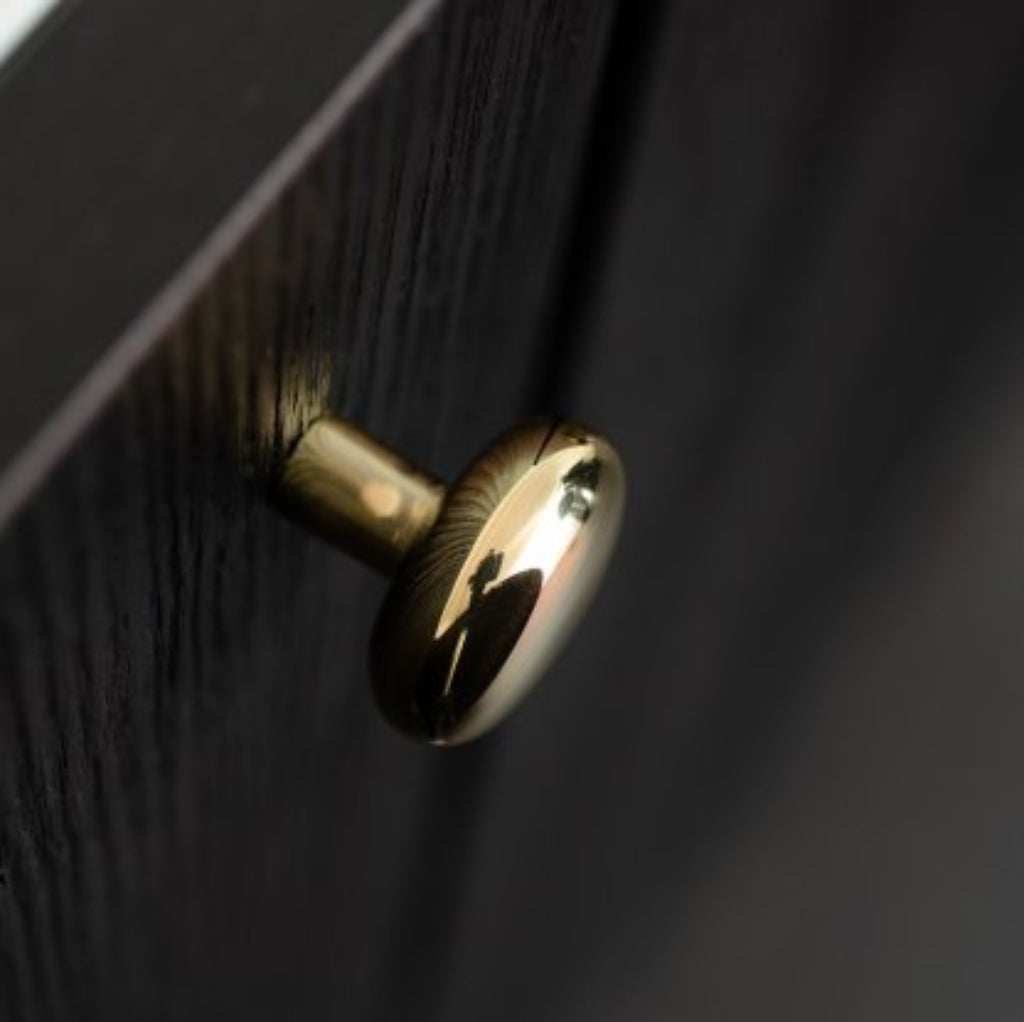 Close-up of a gold cabinet knob on a dark wooden surface