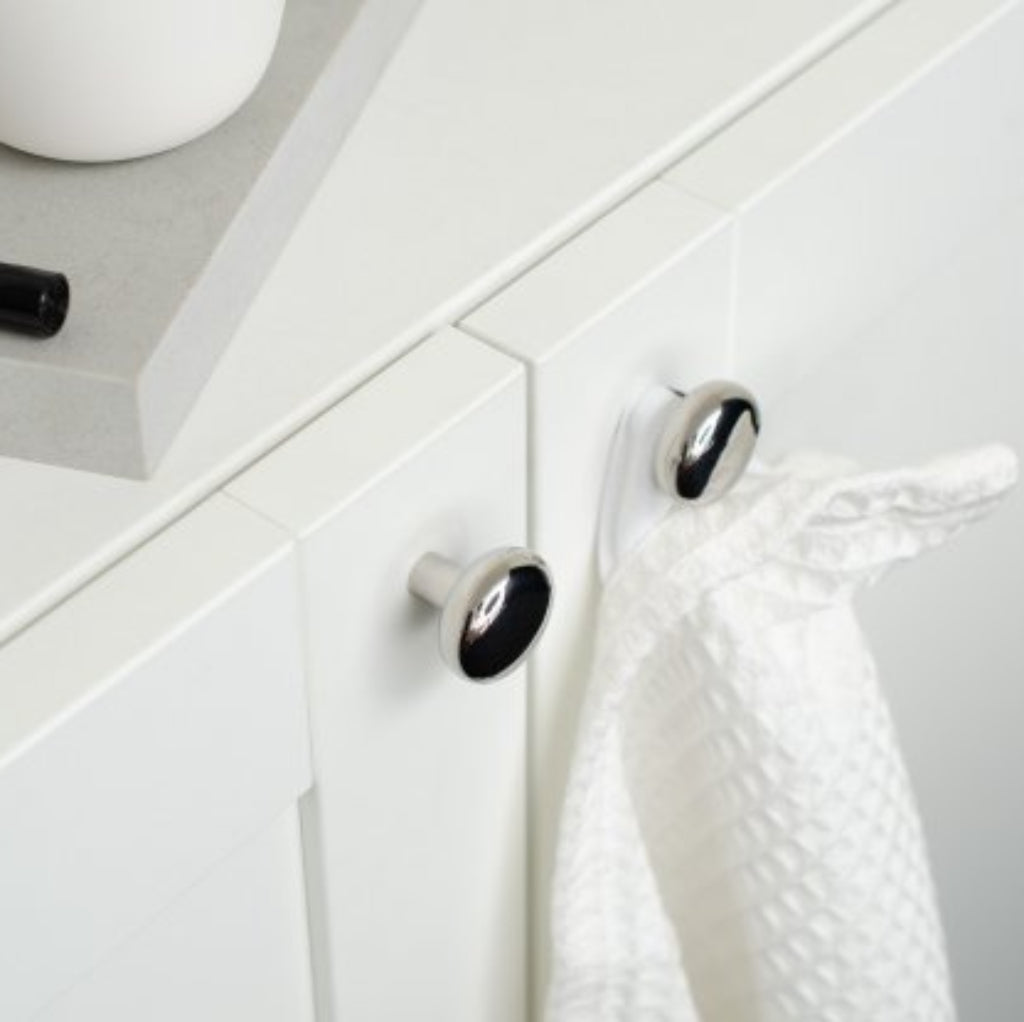 Close-up of a white cabinet with black knobs and a white towel hanging on one of them.