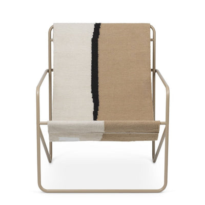 A Ferm Living Cashmere Soil Desert Lounge Chair with a blanket on top of it.