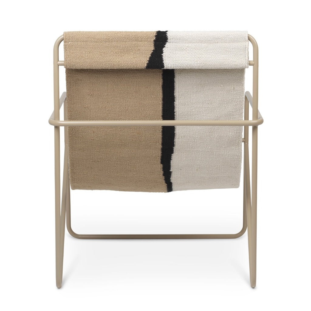 A Cashmere Soil Desert Lounge Chair by Ferm Living with a blanket on top of it.