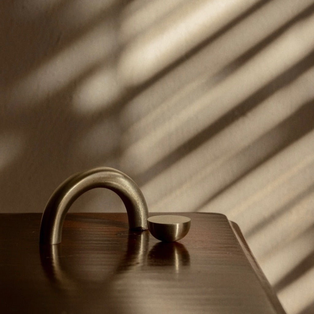 Brass Maha Alavi Cercle arch pull with a small dome knob on wood.