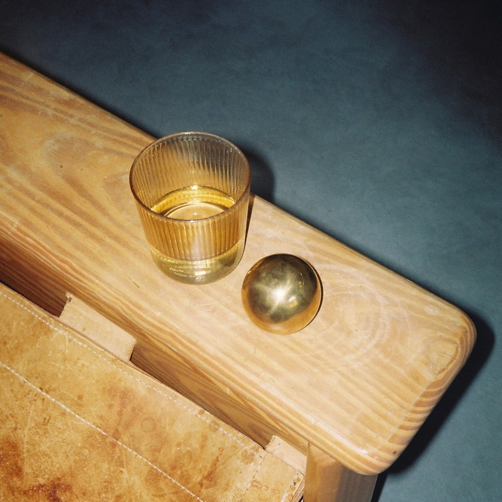 Brass Maha Alavi Cercle knob on a wood shelf.